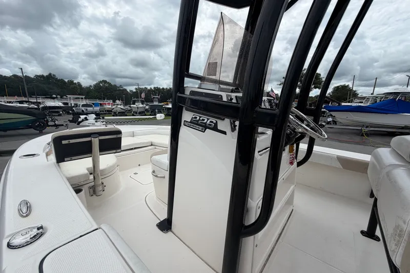 Slide: The Image of 2019 Robalo 226 Cayman boat interior with steering console, docked under cloudy skies. - 31