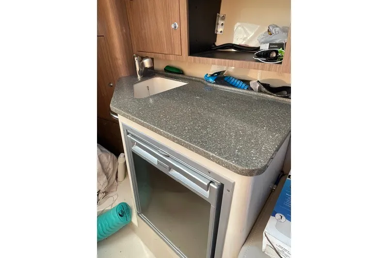 Slide: The Image of 2012 Boston Whaler 285 Conquest cabin interior with sink and mini fridge. - 15