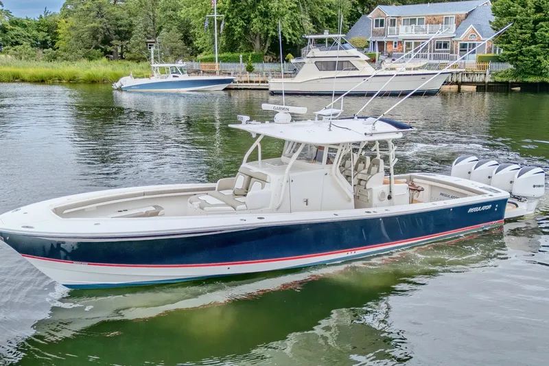 Slide: The Image of 2018 Regulator 41 boat cruising on a serene waterway near a dockside house. - 7
