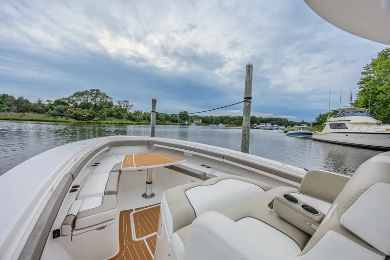 Slide: The Image of Luxurious 2018 Regulator 41 boat interior with seating and table, docked by a scenic waterfront. - 20