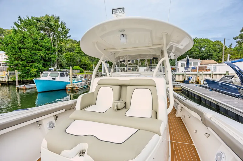 Slide: The Image of 2018 Regulator 41 boat with cushioned seating, docked in a marina with surrounding greenery. - 16