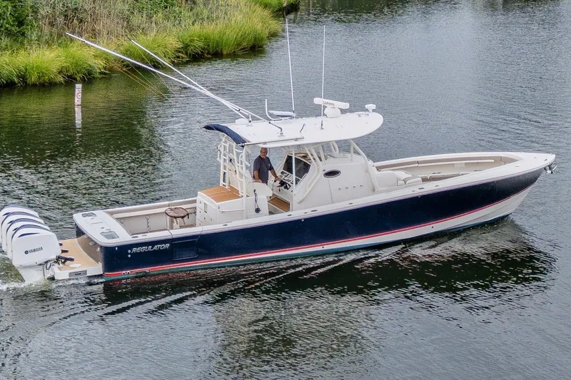 Slide: The Image of 2018 Regulator 41 boat cruising on a calm waterway with lush greenery. - 8