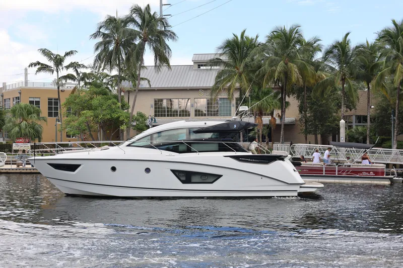 The Image of 2019 Beneteau Gran Turismo 50 yacht docked near palm trees and waterfront buildings. - 1