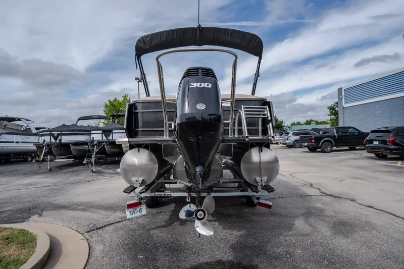 Slide: The Image of 2023 Crest Caribbean LX 250 pontoon boat with powerful 300 HP engine, parked outdoors. - 23