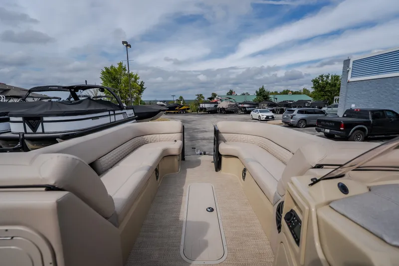Slide: The Image of 2023 Crest Caribbean LX 250 pontoon boat with beige seating, parked in a marina. - 52