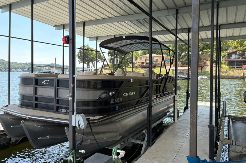Slide: The Image of 2023 Crest Caribbean LX 250 pontoon boat docked in a covered marina. - 11