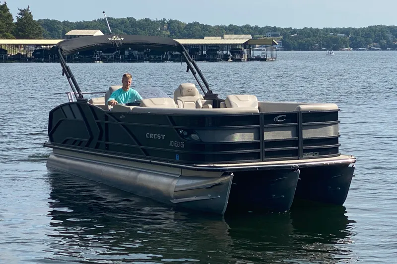 Slide: The Image of 2023 Crest Caribbean LX 250 pontoon boat on a lake with a person driving. - 62