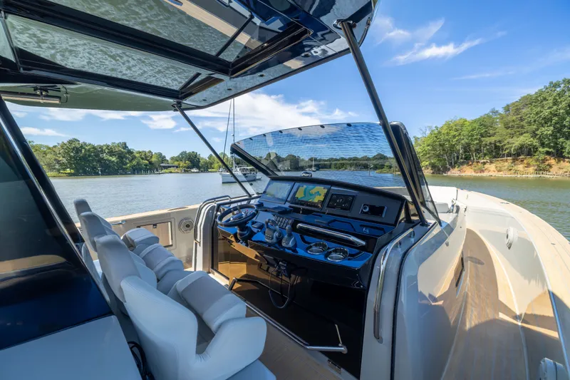 Slide: The Image of 2023 Pardo Yachts 43 cockpit with modern controls, overlooking serene waters and lush greenery. - 30