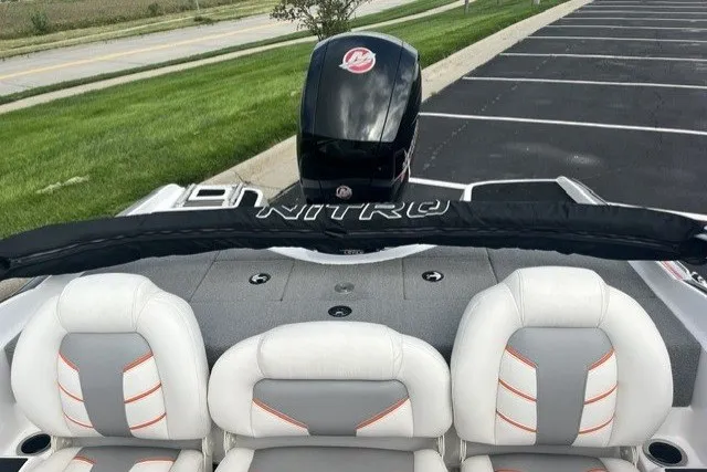 Slide: The Image of 2021 Nitro Z19 boat interior with cushioned seats and motor, parked near a road. - 9