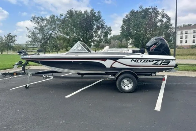 Slide: The Image of 2021 Nitro Z19 boat on trailer in parking lot, surrounded by trees and buildings. - 1