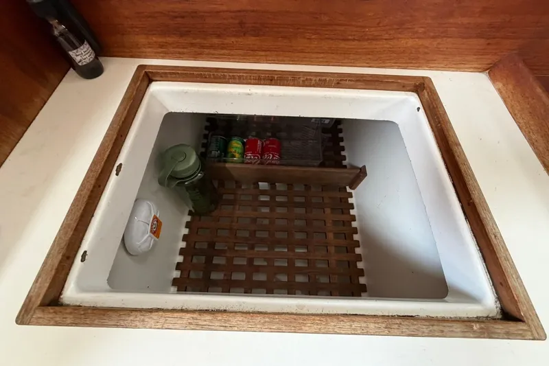 Slide: The Image of Storage compartment inside a 1980 Tartan 33 boat, featuring wooden trim and canned goods. - 38