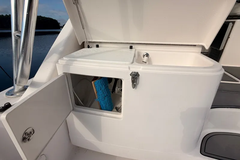 Slide: The Image of 2003 Cabo 35 Express boat storage compartment with open hatch, docked by calm water. - 21