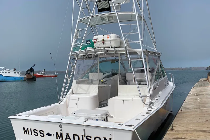 Slide: The Image of 2003 Cabo 35 Express boat docked, featuring a spacious deck and fishing tower. - 5