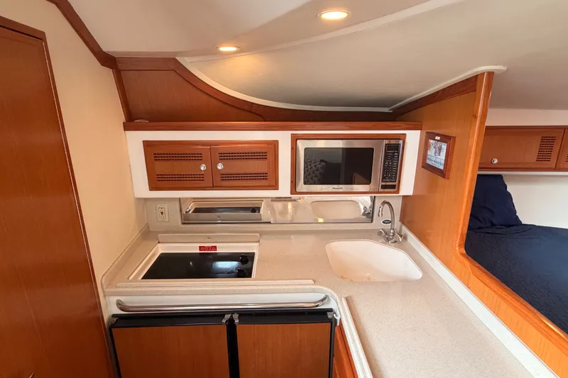 Slide: The Image of 2003 Cabo 35 Express yacht interior kitchen with stove, microwave, and sink. - 45