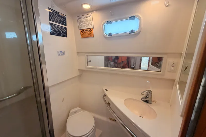 Slide: The Image of 2003 Cabo 35 Express boat bathroom with sink, toilet, and porthole window. - 35