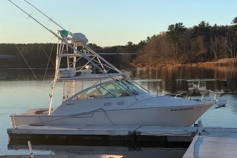 Slide: The Image of 2003 Cabo 35 Express boat docked on a serene lake with wooded shoreline. - 6