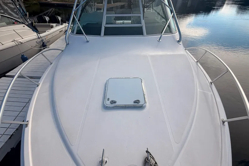 Slide: The Image of 2003 Cabo 35 Express boat deck with hatch, docked beside another vessel. - 10