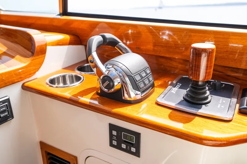 Slide: The Image of Hinckley Picnic Boat 37 MKIII 2020 helm controls with polished wood finish and modern joystick. - 26