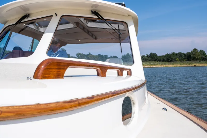 Slide: The Image of 2020 Hinckley Picnic Boat 37 MKIII cruising on a serene lake under a clear blue sky. - 30