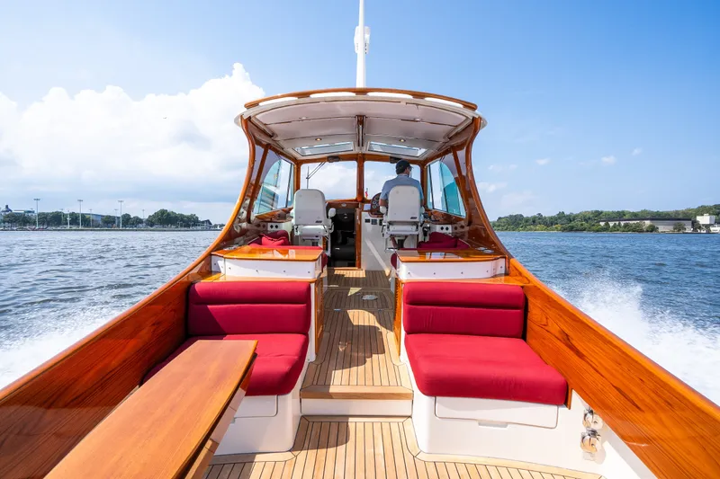 Slide: The Image of 2020 Hinckley Picnic Boat 37 MKIII cruising on water, featuring elegant wooden interior and red seating. - 18