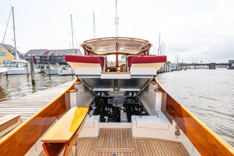 Slide: The Image of 2020 Hinckley Picnic Boat 37 MKIII docked, showcasing open engine compartment and luxurious wooden deck. - 51