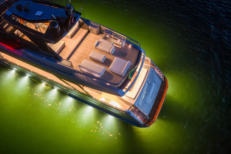 Slide: The Image of Luxurious 2021 Riva 110' Dolcevita yacht illuminated on serene green waters at night. - 26