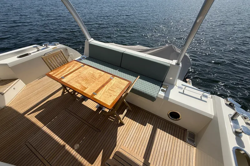 Slide: The Image of Luxurious 2017 Prestige 630 yacht deck with wooden table and seating, overlooking serene water. - 17