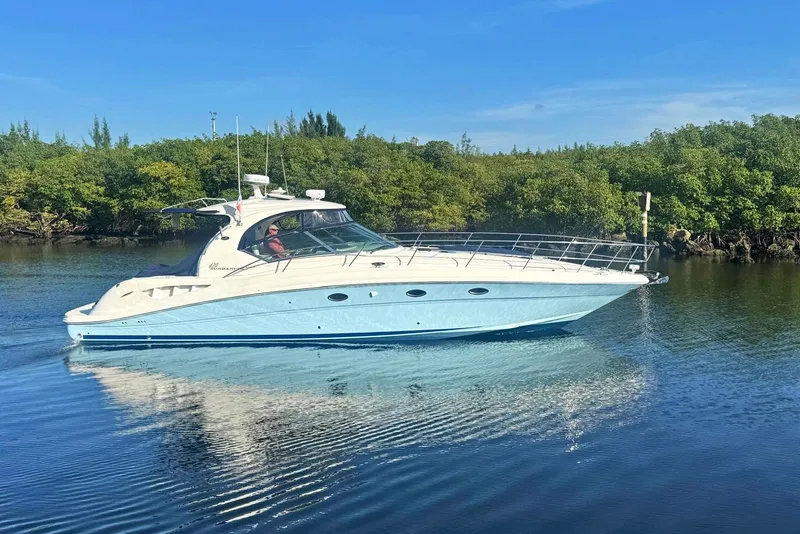 The Image of 2005 Sea Ray 420 Sundancer yacht cruising on calm water with lush greenery background. - 0