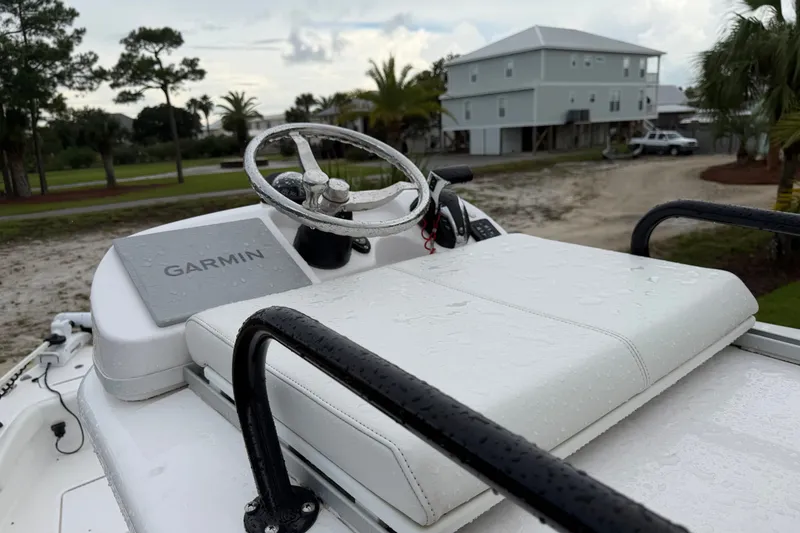 Slide: The Image of 2022 Everglades 243 Center Console boat with Garmin navigation, wet from rain, parked near houses. - 16