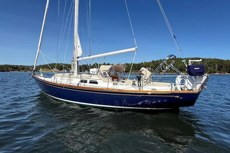 Slide: The Image of 1984 Hinckley Sou'wester 42 sailboat on calm water, clear sky, forested shoreline. - 5