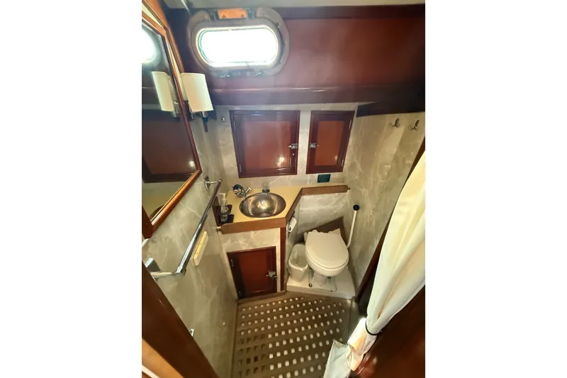Slide: The Image of Compact bathroom in 1984 Hinckley Sou'wester 42 yacht with sink, toilet, and wooden cabinetry. - 54