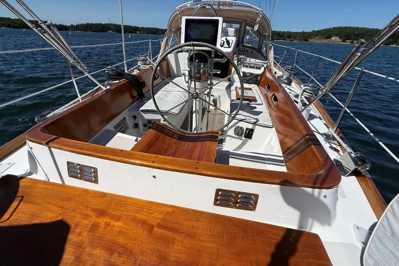 Slide: The Image of 1984 Hinckley Sou'wester 42 sailboat cockpit with wooden trim and steering wheel on open water. - 13