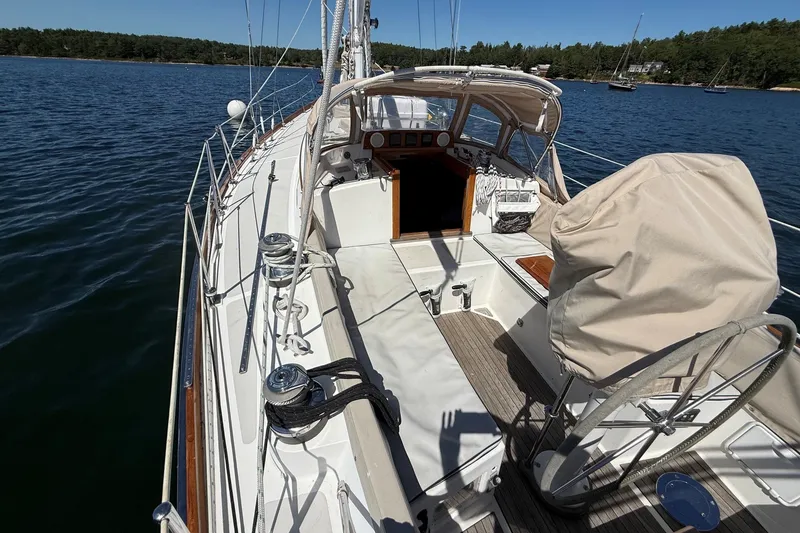 Slide: The Image of Hinckley Sou'wester 42 sailboat deck, 1984 model, on calm water with forested shoreline. - 23