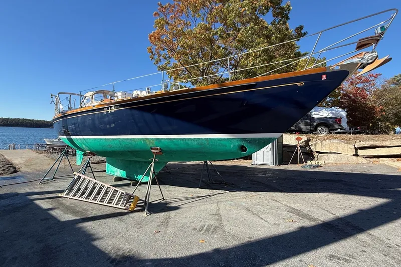 Slide: The Image of 1984 Hinckley Sou'wester 42 sailboat on stands by the water, clear blue sky. - 62