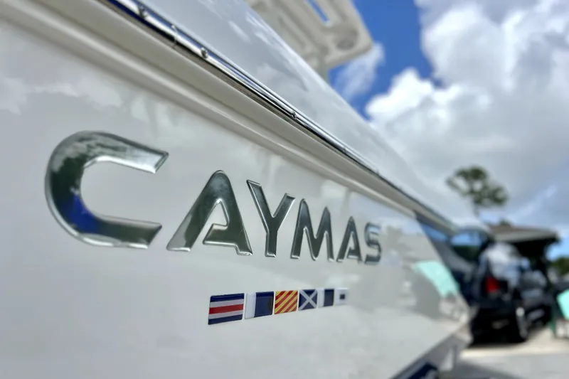 Slide: The Image of 2020 Caymas 26 HB boat with logo and nautical flags, under a bright sky. - 21