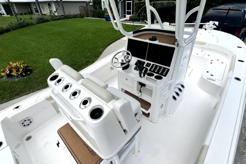 Slide: The Image of 2020 Caymas 26 HB boat interior with modern helm and seating, parked in a driveway. - 26