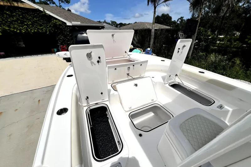 Slide: The Image of 2020 Caymas 26 HB boat with open storage compartments and seating, outdoors. - 80