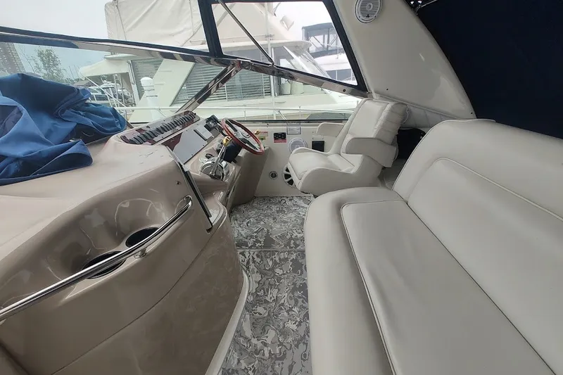 Slide: The Image of 1998 Sea Ray Sundancer 400 cockpit with beige seating and helm, docked at marina. - 7