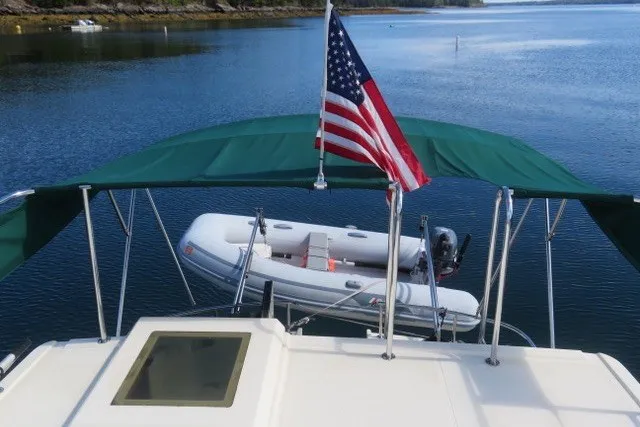 Slide: The Image of Nordic Tug 32 (2001) with American flag and dinghy on calm water. - 9