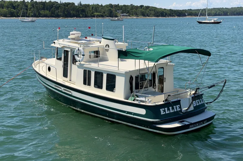 Slide: The Image of 2001 Nordic Tug 32 boat with green canopy on calm water. - 3