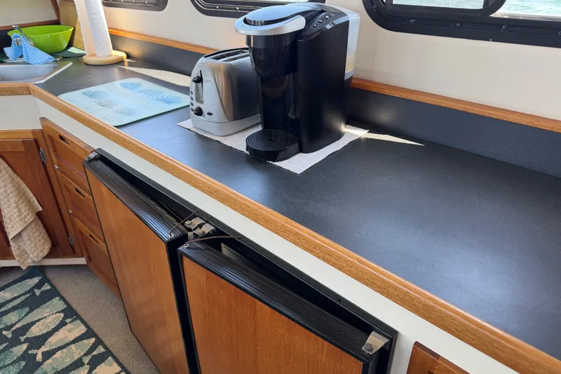 Slide: The Image of Kitchen area of a 2001 Nordic Tug 32 with appliances and wooden cabinetry. - 33