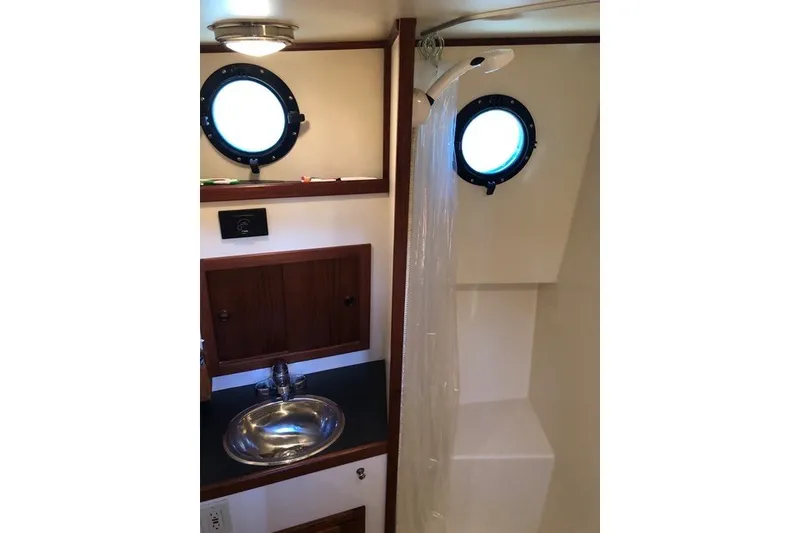 Slide: The Image of Bathroom interior of 2001 Nordic Tug 32 with sink, shower, and porthole window. - 65