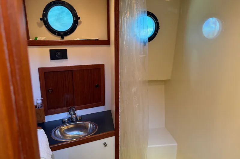 Slide: The Image of Bathroom interior of a 2001 Nordic Tug 32, featuring a sink and porthole window. - 63