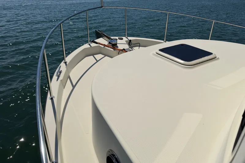 Slide: The Image of Bow view of 2001 Nordic Tug 32 on calm water, showcasing deck and railing. - 16