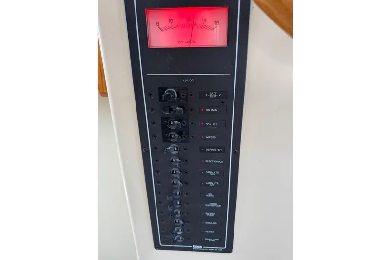 Slide: The Image of Electrical control panel on a 2001 Nordic Tug 32 boat, featuring various switches and a voltmeter. - 53
