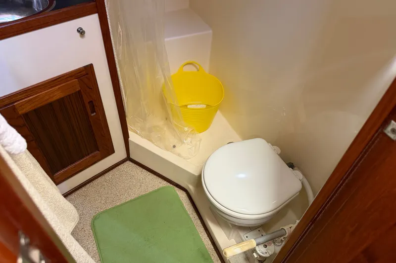 Slide: The Image of Bathroom interior of a 2001 Nordic Tug 32, featuring a toilet and wooden cabinetry. - 62