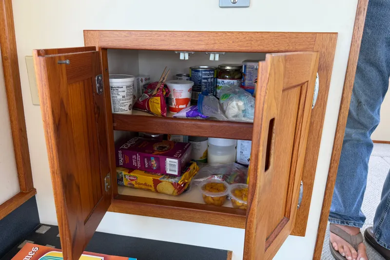 Slide: The Image of Wooden cabinet on 2001 Nordic Tug 32, stocked with snacks and canned goods. - 35