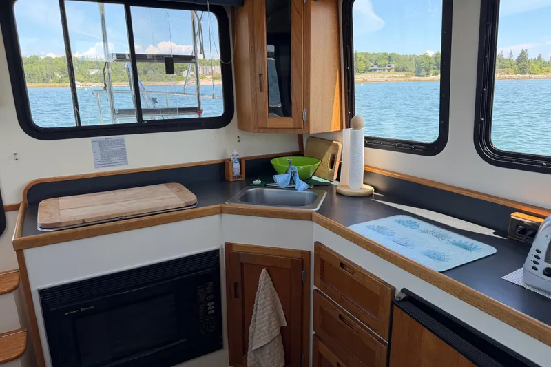 Slide: The Image of Cozy kitchen in a 2001 Nordic Tug 32 boat with scenic water view. - 34
