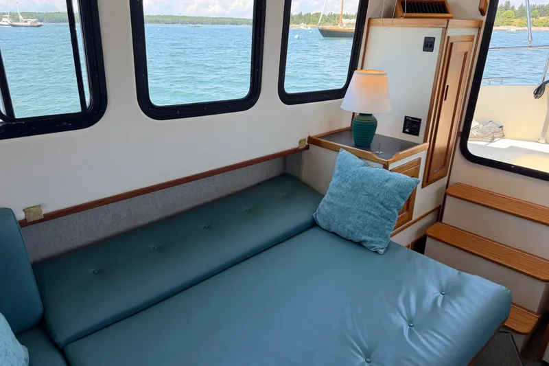Slide: The Image of Interior of 2001 Nordic Tug 32 with teal seating, lamp, and scenic water view. - 30