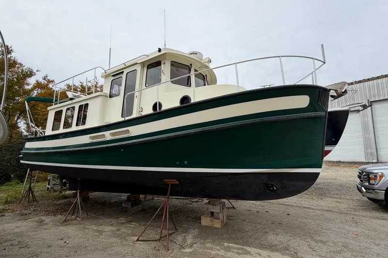 Slide: The Image of 2001 Nordic Tug 32 boat on stands, green and cream exterior, outdoors. - 88